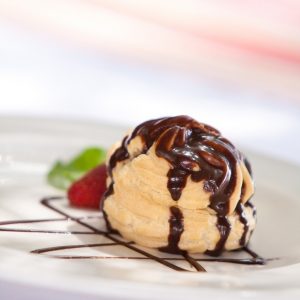 Chocolate profiterole stuffed with ice cream served on a plate